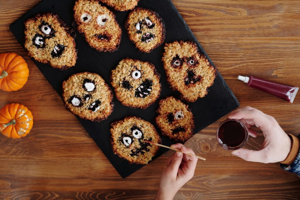 A selection of halloween themed cookies, being hand decorated with ghoulish faces